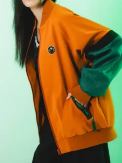 Close-up of Melinoë Model Hades II Blouson Orange And Green Jacket
